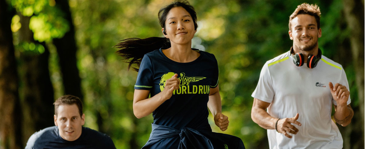 Τρεις συμμετέχοντες στο Wings for Life World Run τρέχουν χαρούμενοι, φορώντας αθλητικά ακουστικά Philips.